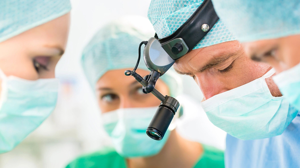 A group of surgeons from Princeton and Millburn, NJ., looking at a microscope.